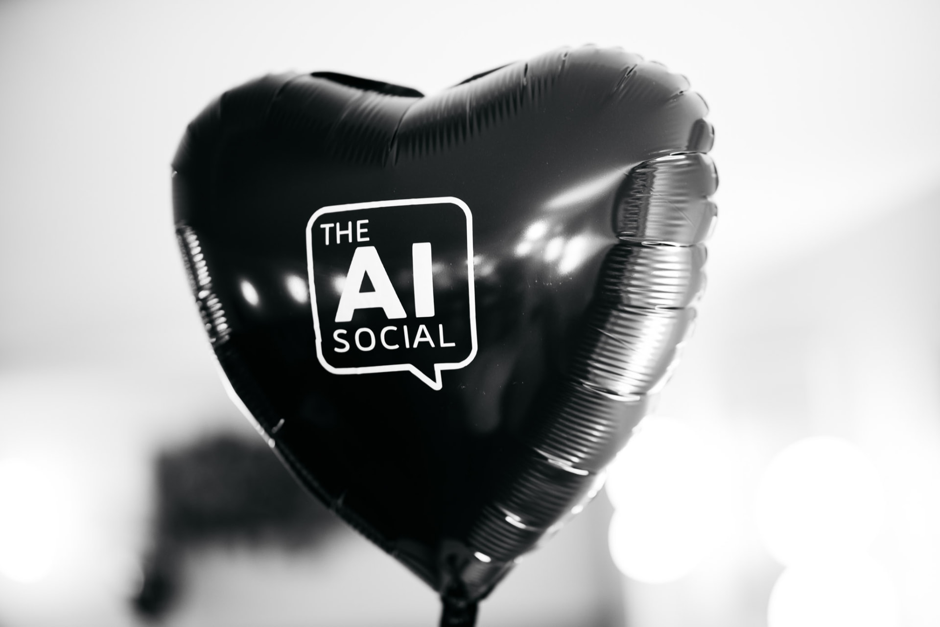 Close-up of a black heart-shaped balloon with The AI Social logo