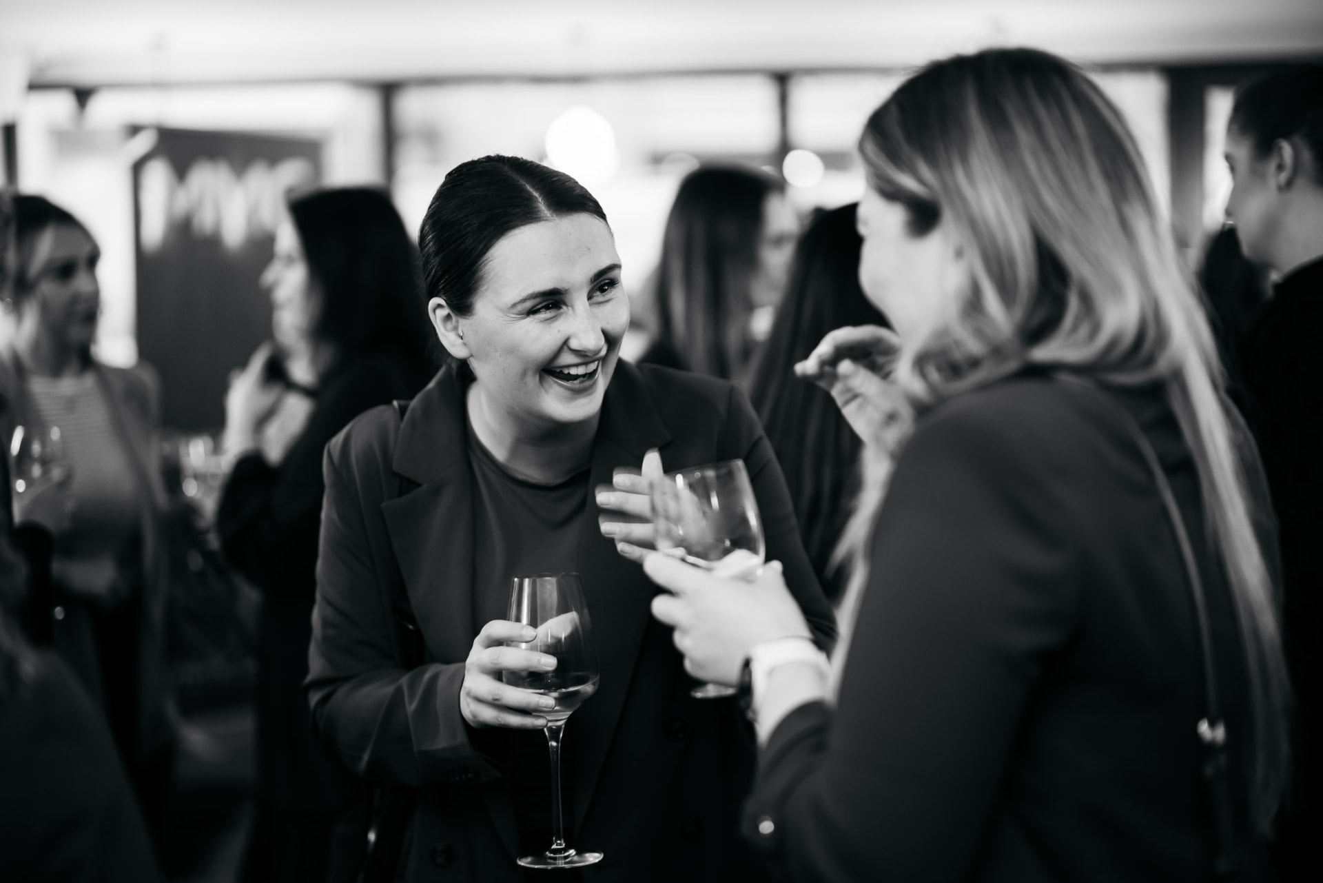 Guests sharing a laugh with wine at the launch